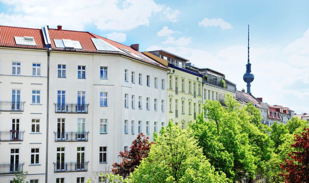 Mehrere sanierte Altbauten mit roten Daechern und Blick auf den Fernsehturm in Berlin – Symbol fuer wohnungssanierung berlin im urbanen Kontext